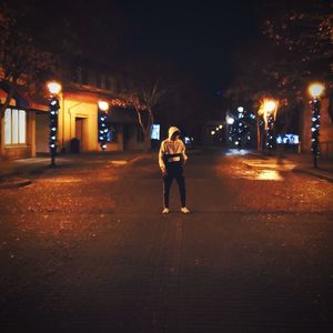 Rear view of man on illuminated street at night