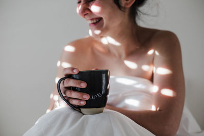 Midsection of smiling woman holding coffee cup