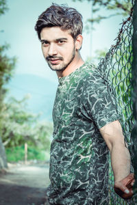 Portrait of young man standing against plants