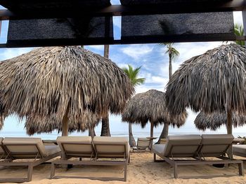 Lounge chairs and tables on beach against sky