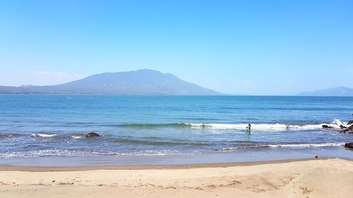 Scenic view of beach against clear blue sky