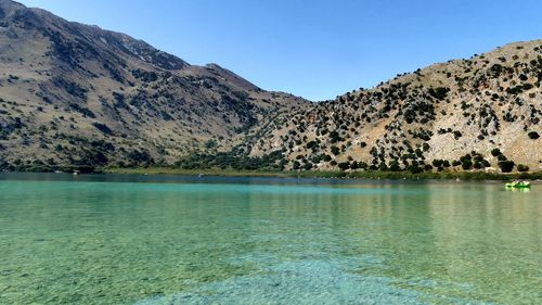 Scenic view of lake and mountains against clear blue sky