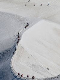 People skiing on snow covered landscape against cloudy sky