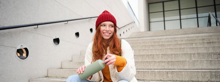 Portrait of young woman standing against wall