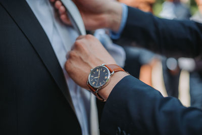 Midsection of man holding watch