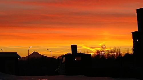 Silhouette of factory against orange sky