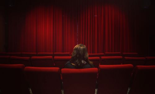 Rear view of woman sitting on chair in room