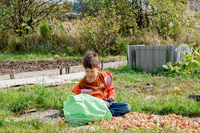 The boy is harvesting in the village. child labour. child collects onions
