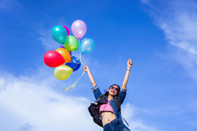 Low angle view of woman holding balloons