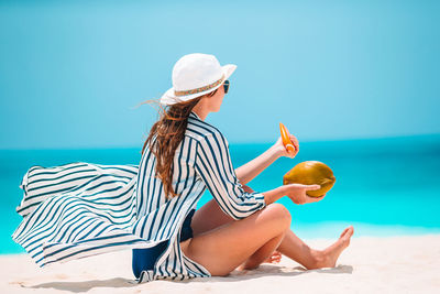 Midsection of woman sitting on beach