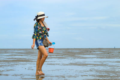 Full length of woman holding bucket at beach