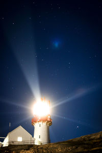 Illuminated lighthouse against sky at night