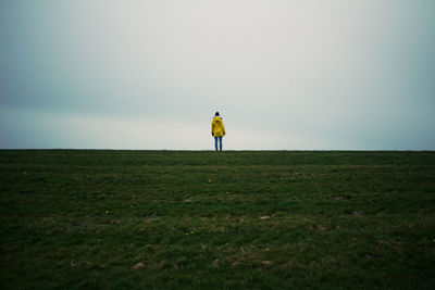 Rear view of woman standing on field against sky