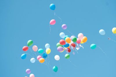 Low angle view of balloons against clear blue sky