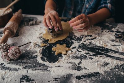 Small hand baking christmas cookies with rolling pin and flour 