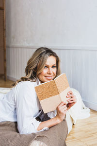 Portrait of smiling young woman sitting on bed at home