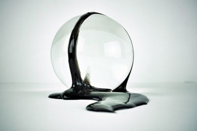 Close-up of crystal ball on table against white background