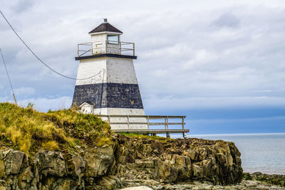 Lighthouse by sea against sky