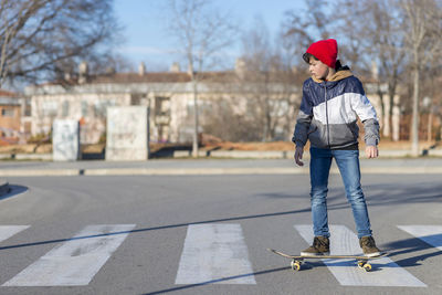 Portrait of boy skateboarding on road against trees