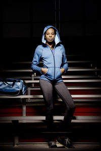 Portrait of young woman standing against illuminated wall