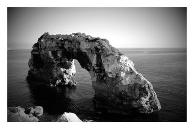 Rock formation in sea against clear sky