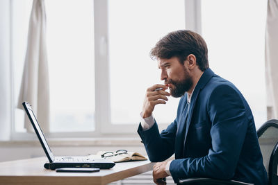 Young man using mobile phone while sitting at office