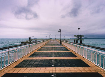 Walk on the pier over sea against sky in the early morning.