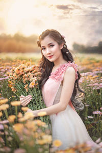 Portrait of smiling young woman standing against plants