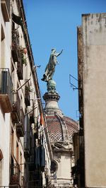 Low angle view of statue against buildings