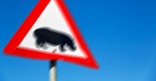 Low angle view of road sign against clear blue sky