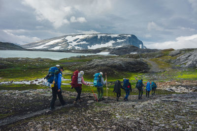 Rear view of people walking on landscape against mountains