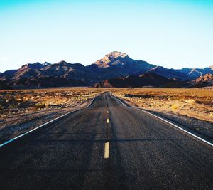 Empty road along landscape and mountains against sky