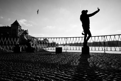 Silhouette man with arms raised against sky