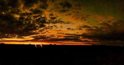 Silhouette landscape against dramatic sky at sunset