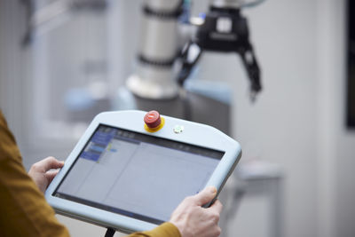 Hands of engineer holding robot controller in industry