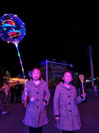 Portrait of happy girl holding illuminated light painting at night