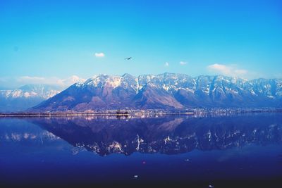 Scenic view of lake by mountains against blue sky