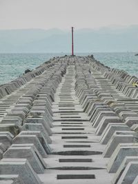 Staircase leading towards sea against clear sky