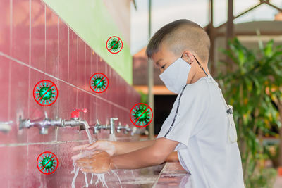 Side view of boy standing against wall