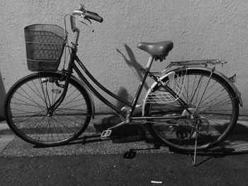 Bicycle parked against pole on wall