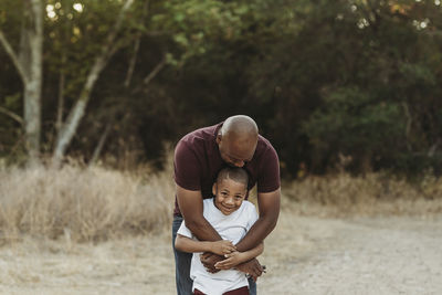 Close up of happy father and son hugging in backlit field