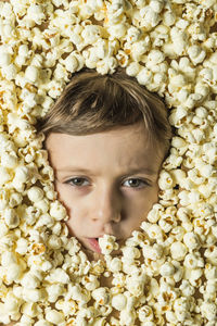 Close-up portrait of boy covered with popcorn