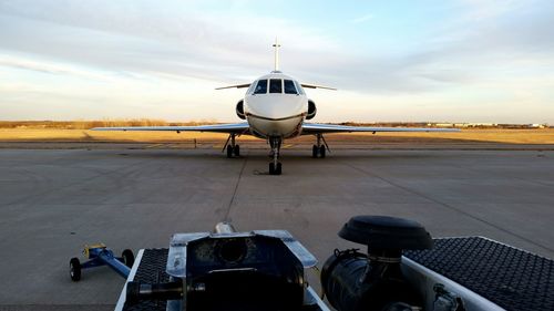 Airplane on runway against cloudy sky