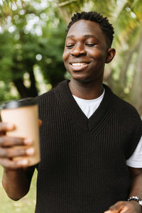 Young african man with to go coffee cup on street outdoor