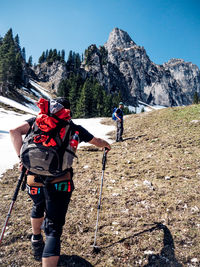 Rear view of people walking on mountain against sky