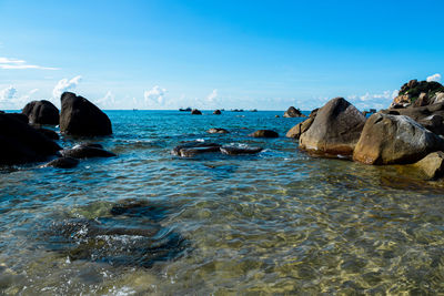 Scenic view of rocks in sea against blue sky