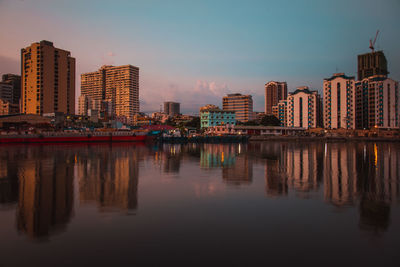 Reflection of illuminated buildings in the city against the pasig river on a sunset.