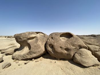 Rocks on sand against clear sky