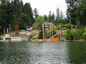 House by lake and trees against sky