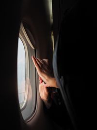 Cropped image of person by window in airplane 